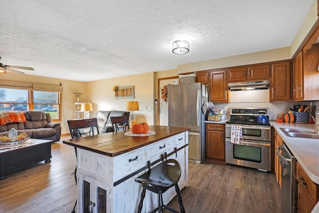 kitchen with a textured ceiling, stainless steel appliances, dark hardwood / wood-style floors, and sink