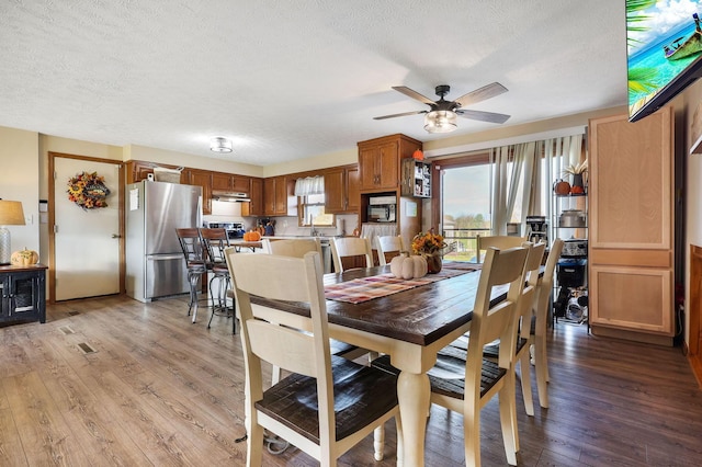 dining room featuring hardwood / wood-style floors, a textured ceiling, and ceiling fan