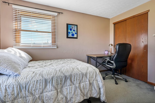 carpeted bedroom with a textured ceiling and a closet