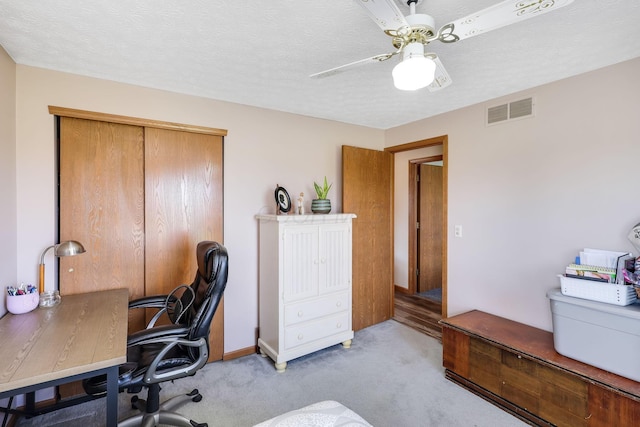 carpeted office space featuring ceiling fan and a textured ceiling