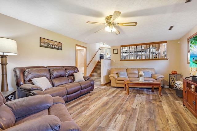 living room with a textured ceiling, light hardwood / wood-style floors, and ceiling fan