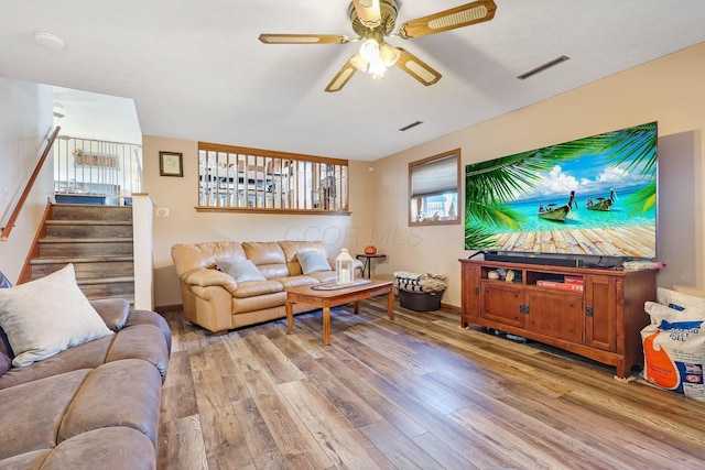 living room featuring a textured ceiling, light wood-type flooring, and ceiling fan