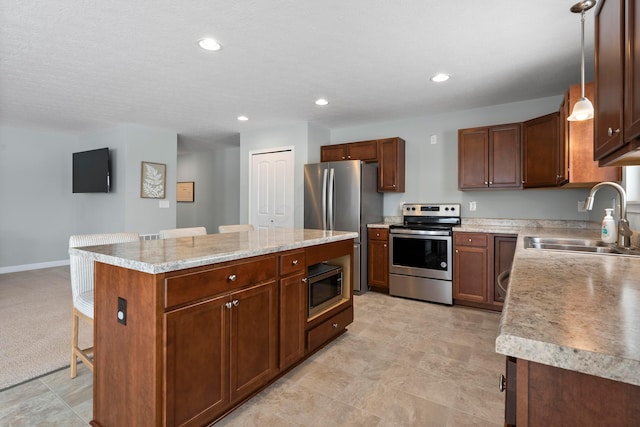 kitchen featuring a center island, sink, hanging light fixtures, a kitchen bar, and stainless steel appliances