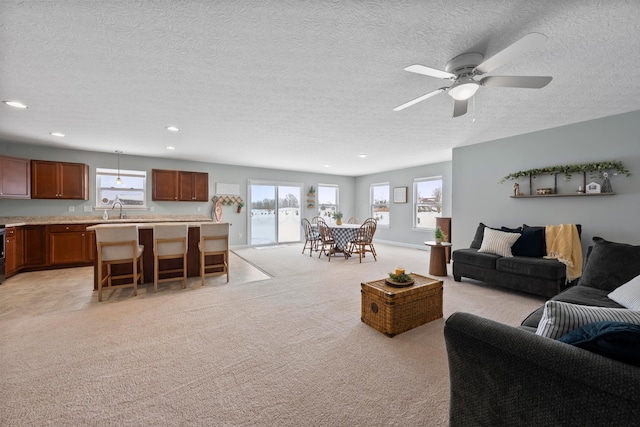 living room featuring light carpet, ceiling fan, plenty of natural light, and a textured ceiling