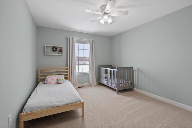 bedroom featuring ceiling fan, light carpet, and a textured ceiling