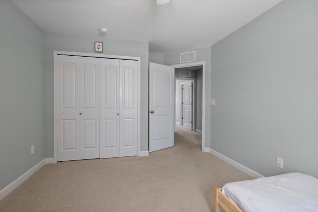 carpeted bedroom with a closet and a textured ceiling