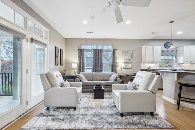 living room with light hardwood / wood-style floors, ceiling fan, a healthy amount of sunlight, and sink