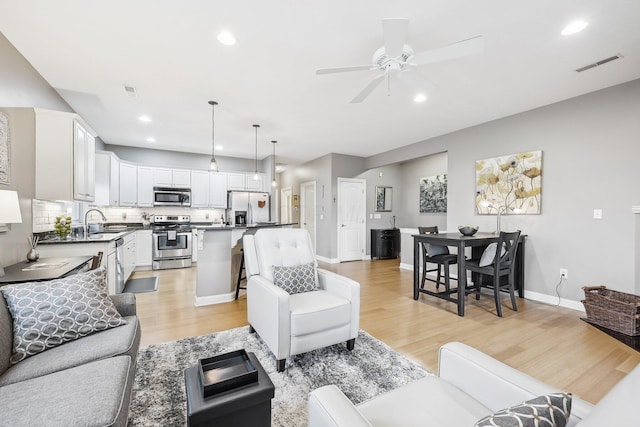 living room with ceiling fan, light hardwood / wood-style flooring, and sink