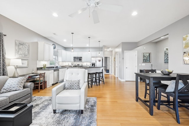 living room featuring ceiling fan, light hardwood / wood-style floors, and sink