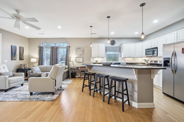 kitchen featuring a center island, stainless steel appliances, tasteful backsplash, white cabinets, and a kitchen breakfast bar