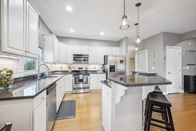 kitchen featuring sink, decorative light fixtures, a center island, white cabinetry, and appliances with stainless steel finishes