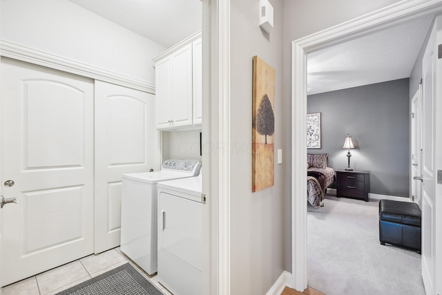 clothes washing area with cabinets, washing machine and clothes dryer, and light carpet