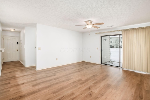 empty room with ceiling fan, light hardwood / wood-style floors, and a textured ceiling