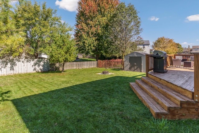 view of yard featuring a deck, a storage shed, and an outdoor fire pit