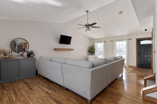 living room featuring a textured ceiling, ceiling fan, hardwood / wood-style flooring, and lofted ceiling