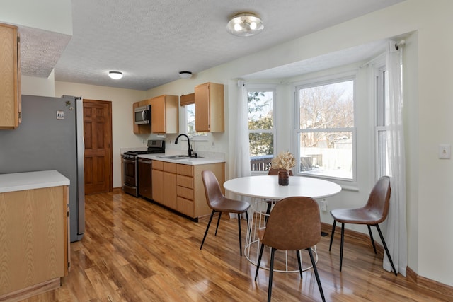 kitchen featuring light hardwood / wood-style flooring, sink, a textured ceiling, appliances with stainless steel finishes, and light brown cabinets