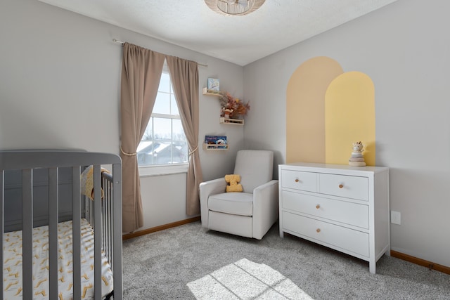 carpeted bedroom featuring a crib and a textured ceiling