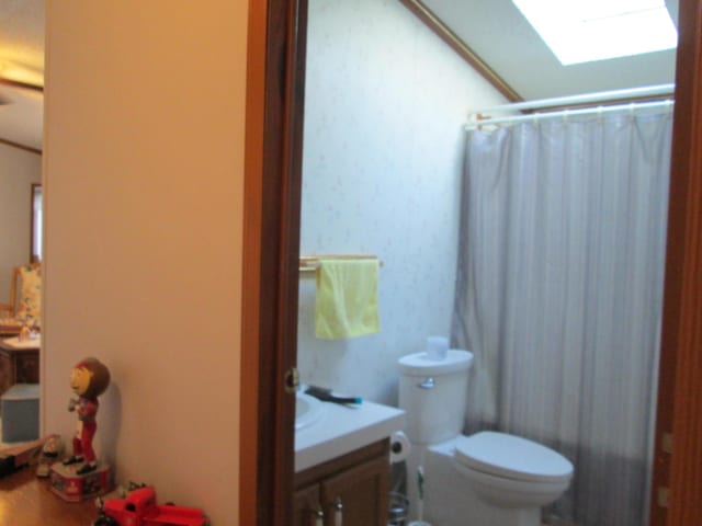 full bathroom with curtained shower, a skylight, vanity, and toilet