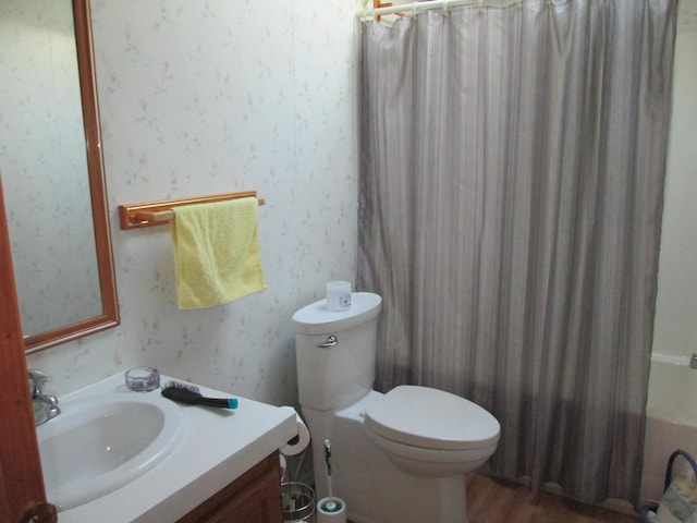 full bathroom with shower / bath combination with curtain, toilet, vanity, wood finished floors, and wallpapered walls