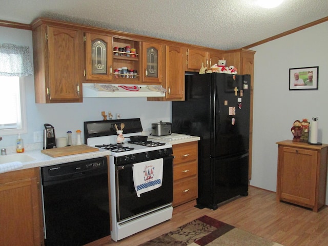 kitchen with exhaust hood, light wood-type flooring, a textured ceiling, crown molding, and black appliances