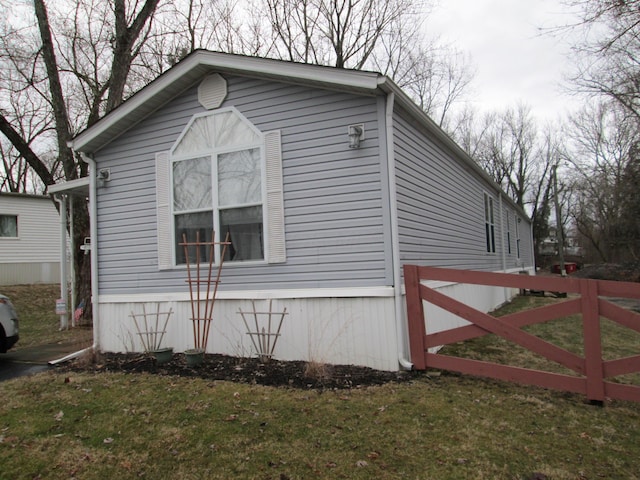 view of side of home with fence and a lawn