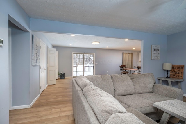 living room featuring recessed lighting, baseboards, light wood-style floors, and a textured ceiling