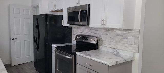 kitchen featuring light stone countertops, stainless steel appliances, tasteful backsplash, hardwood / wood-style floors, and white cabinets