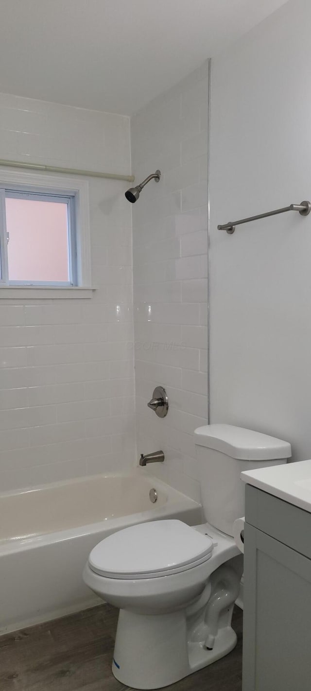 full bathroom with vanity, wood-type flooring, tiled shower / bath combo, and toilet