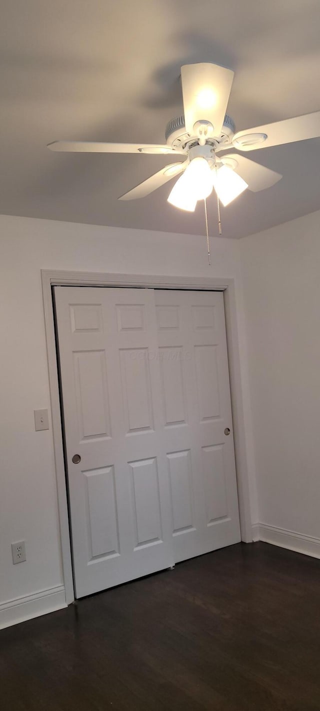 unfurnished bedroom with a closet, ceiling fan, and dark wood-type flooring