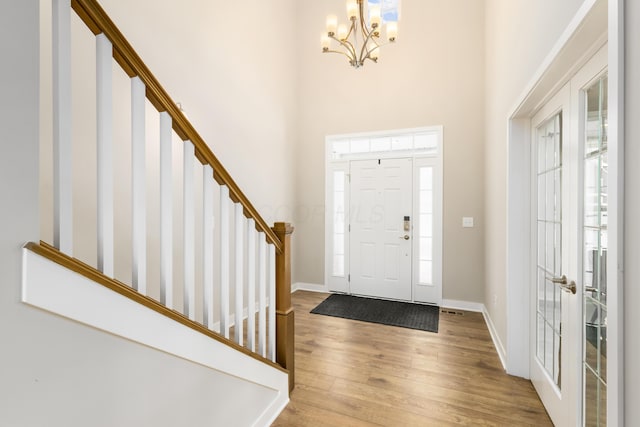 entryway featuring an inviting chandelier, light hardwood / wood-style floors, a high ceiling, and french doors