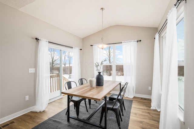 dining space with a notable chandelier, light wood-type flooring, and lofted ceiling