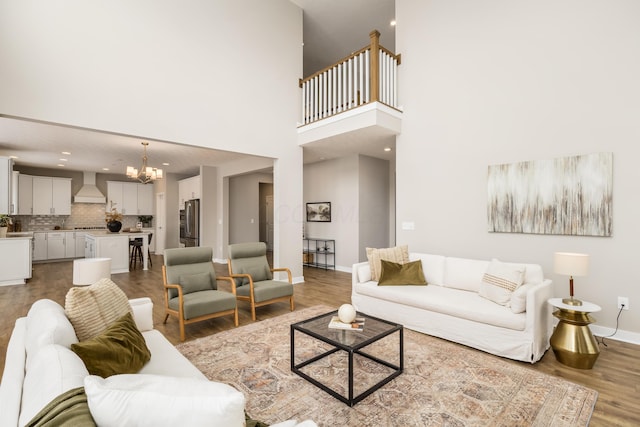 living room featuring wood-type flooring, a towering ceiling, and a chandelier