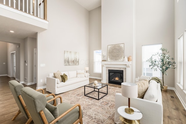 living room with a tile fireplace, a high ceiling, and hardwood / wood-style flooring