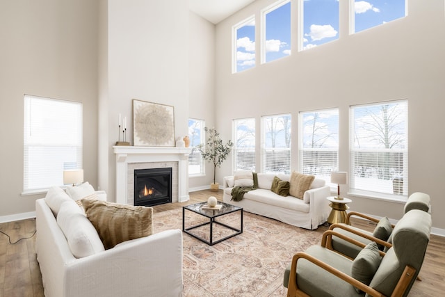 living room featuring a fireplace, a towering ceiling, and light wood-type flooring