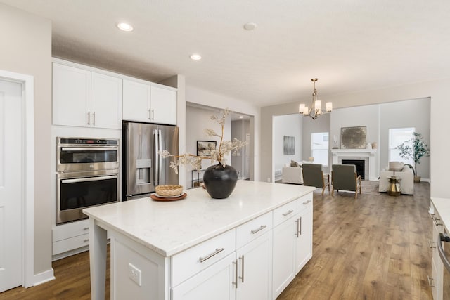 kitchen featuring pendant lighting, a center island, appliances with stainless steel finishes, light hardwood / wood-style floors, and white cabinetry