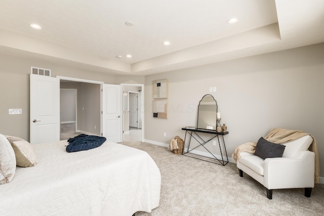 bedroom with a tray ceiling and light colored carpet