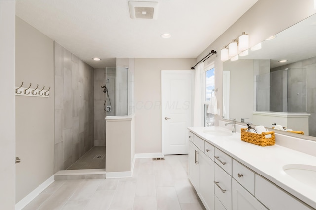 bathroom with tile patterned flooring, vanity, and tiled shower