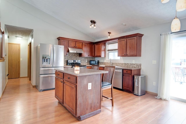 kitchen featuring lofted ceiling, hanging light fixtures, light hardwood / wood-style flooring, a kitchen island, and stainless steel appliances