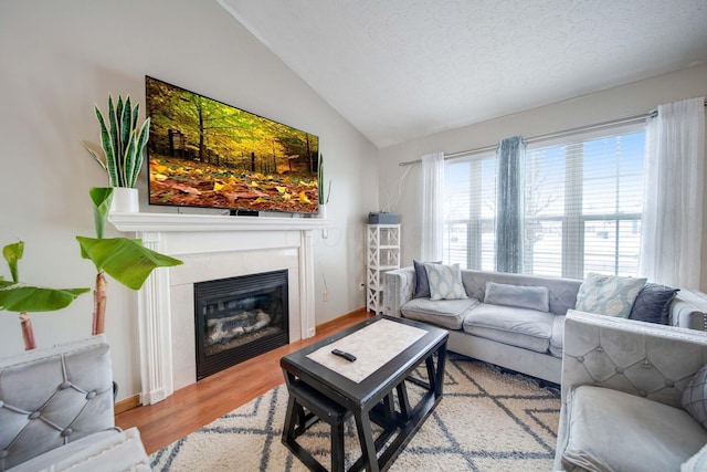 living room featuring a textured ceiling, light hardwood / wood-style floors, and lofted ceiling