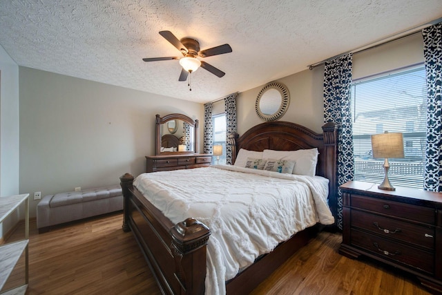 bedroom with a textured ceiling, dark hardwood / wood-style floors, and ceiling fan