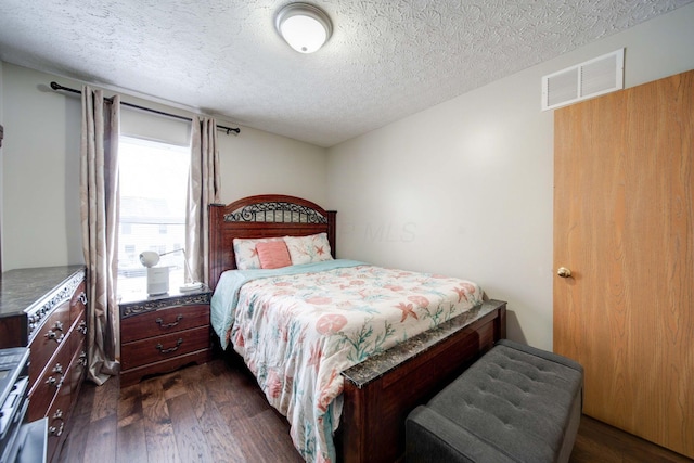 bedroom with a textured ceiling and dark wood-type flooring