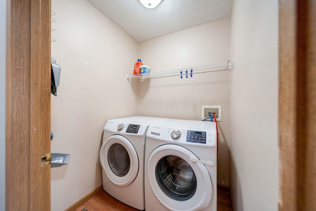 laundry area with a textured ceiling, light hardwood / wood-style flooring, and washer and clothes dryer