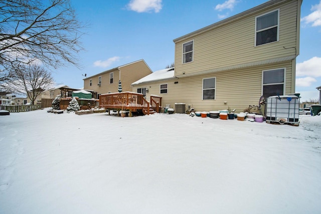 snow covered back of property with central air condition unit and a wooden deck