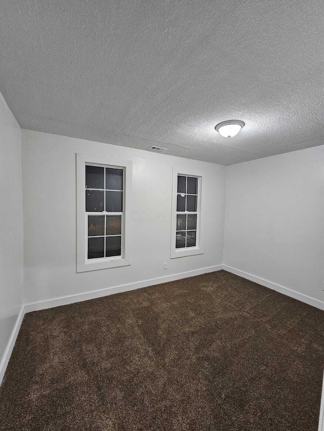 unfurnished room with carpet and a textured ceiling