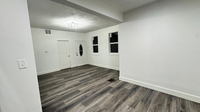 unfurnished room with dark wood-type flooring and a textured ceiling