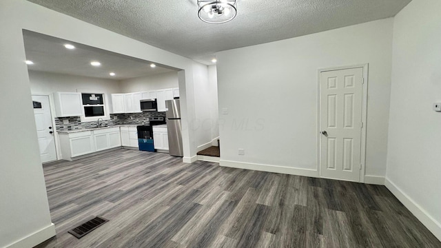 kitchen with backsplash, a textured ceiling, stainless steel appliances, white cabinets, and dark hardwood / wood-style floors