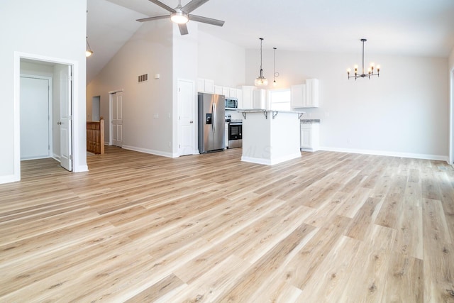 unfurnished living room with ceiling fan with notable chandelier, light hardwood / wood-style floors, and high vaulted ceiling