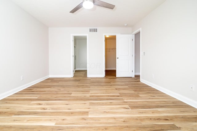 unfurnished bedroom with ceiling fan, light wood-type flooring, a spacious closet, and a closet