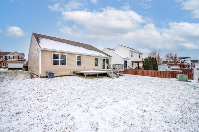 snow covered property with a wooden deck and central AC