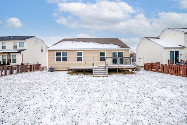 snow covered rear of property with a deck